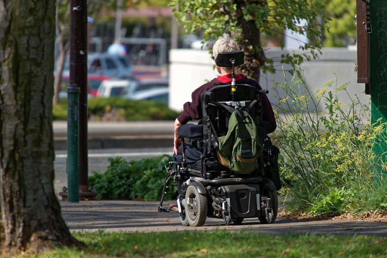A person in a wheelchair using a sidewalk
